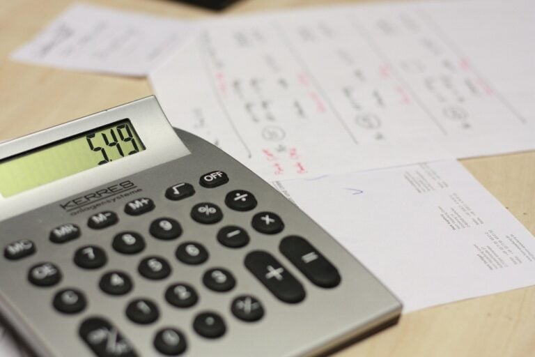A calculator resting on handwritten invoices on a wooden desk
