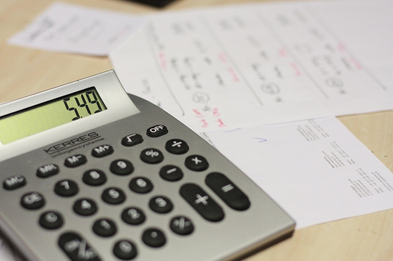 A calculator resting on handwritten invoices on a wooden desk