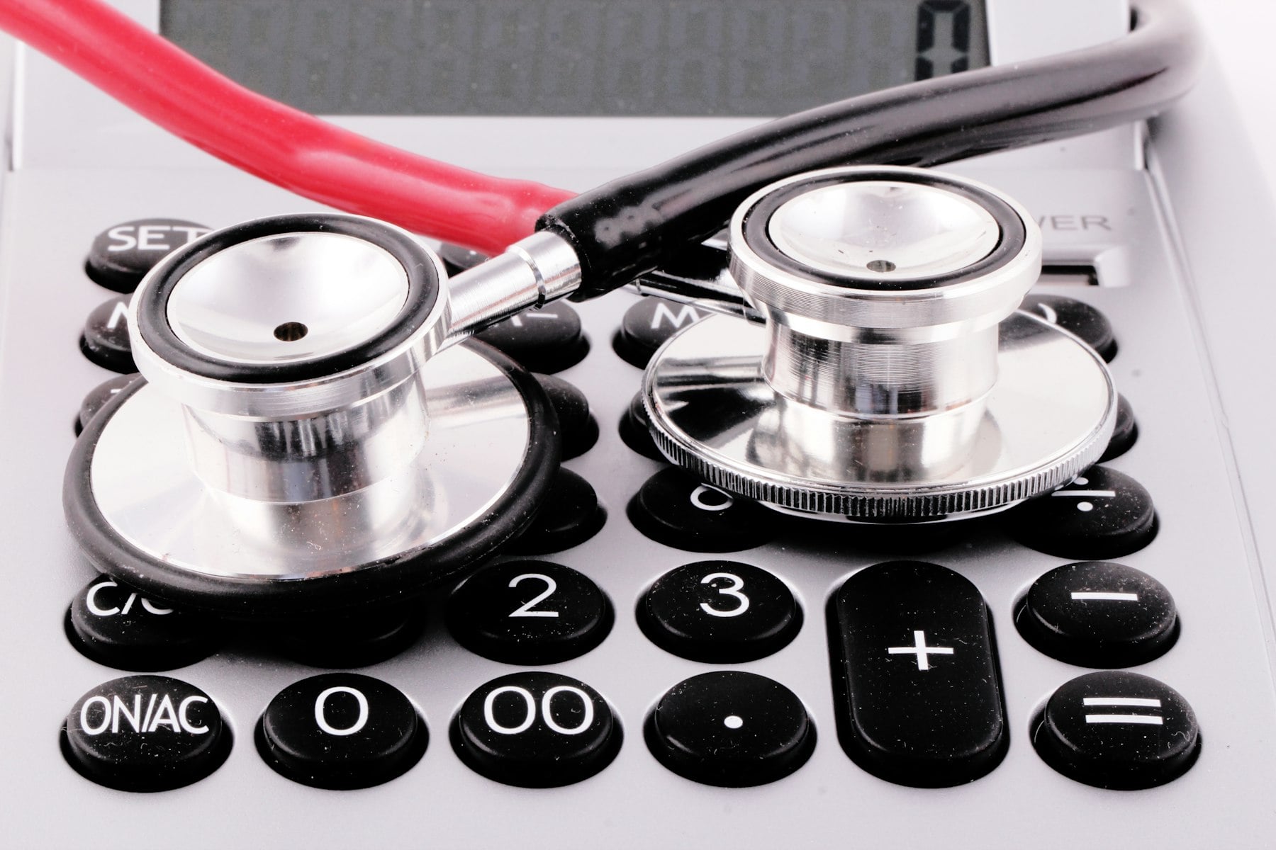 A stethoscope lying across the keys of a calculator