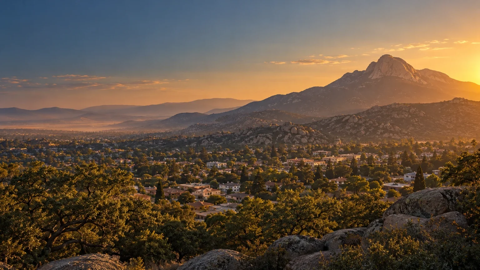Tecate, Baja California at golden hour, with Cerro Cuchumá rising behind the town's rooftops and oak trees